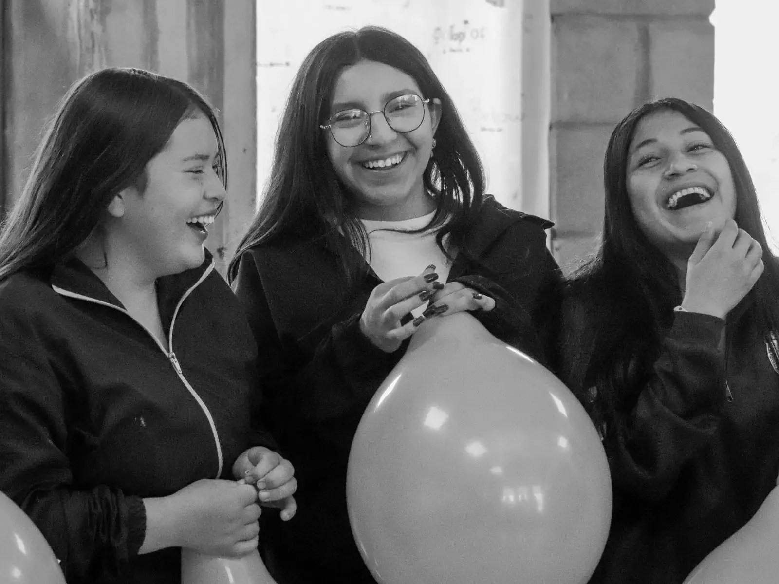 Tres jóvenes riendo juntas en un espacio comunitario de True Identity